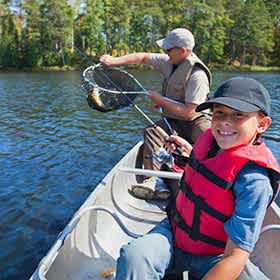 Child and grandfather fishing from boat
