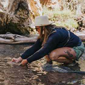Woman fly fishing releasing fish onto water