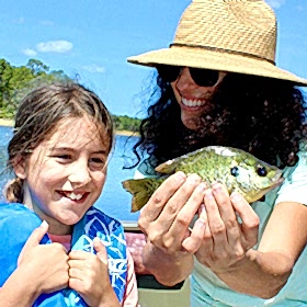 Woman holding fish alongside child 